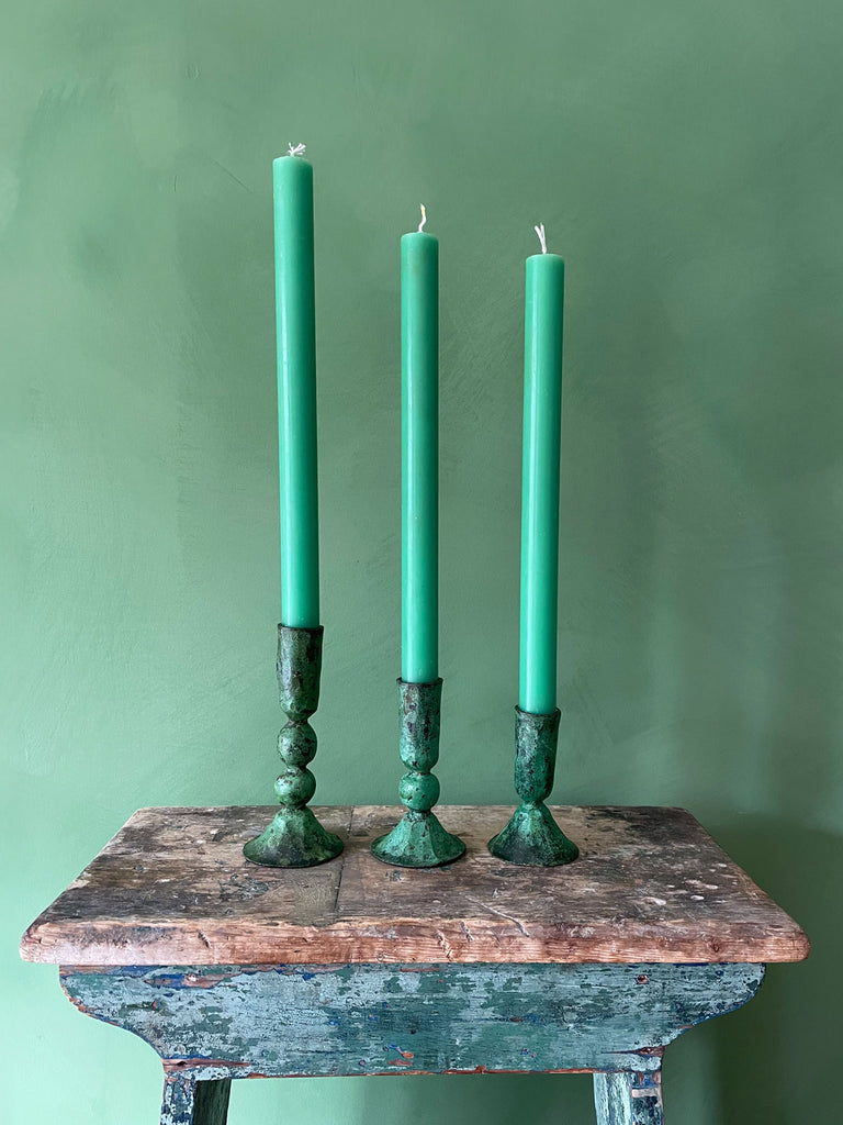 Three elegant artisanal candle holders in antique verdigris patina finish, paired with green dining candles by Bohemia Design