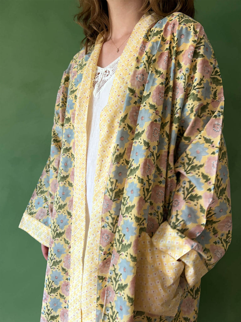 A close-up of a model wearing Bohemia floral block print cotton robe with contrasting pockets and trim in buttermilk yellow.