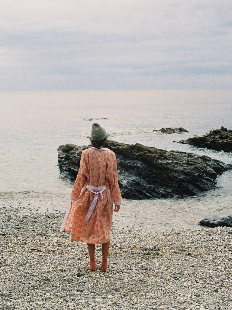 Model on a pebble beach wearing a Bohemia block print robe in lilac.