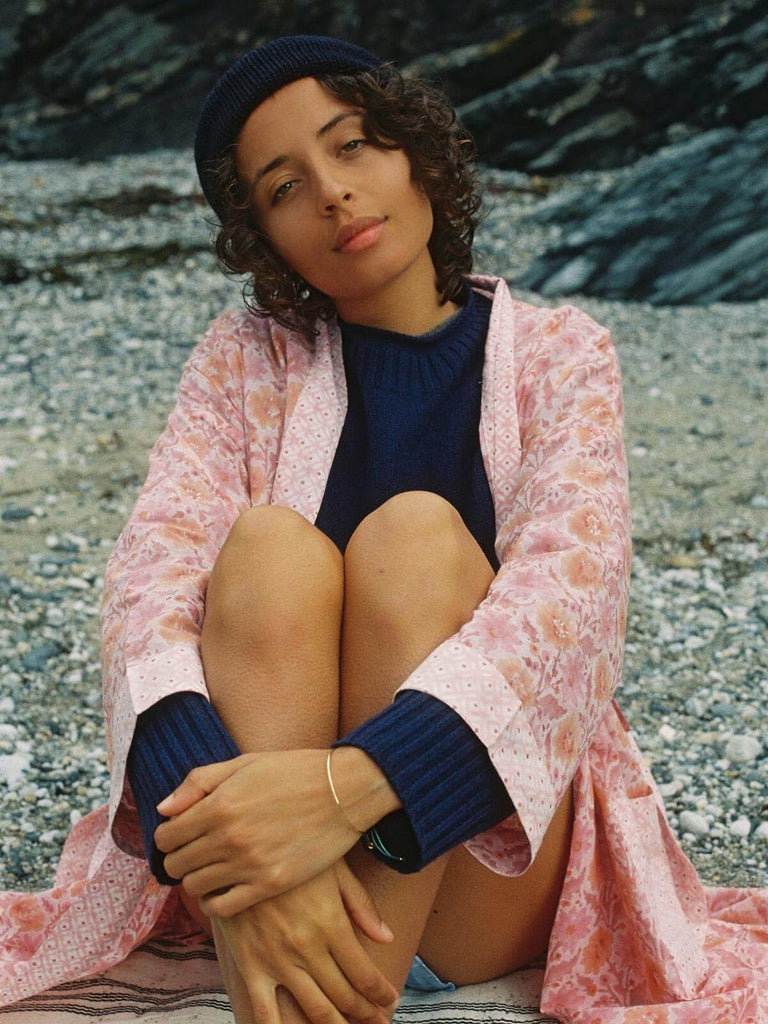 Model in a cosy knit and hat wearing a block print robe on a pebble beach