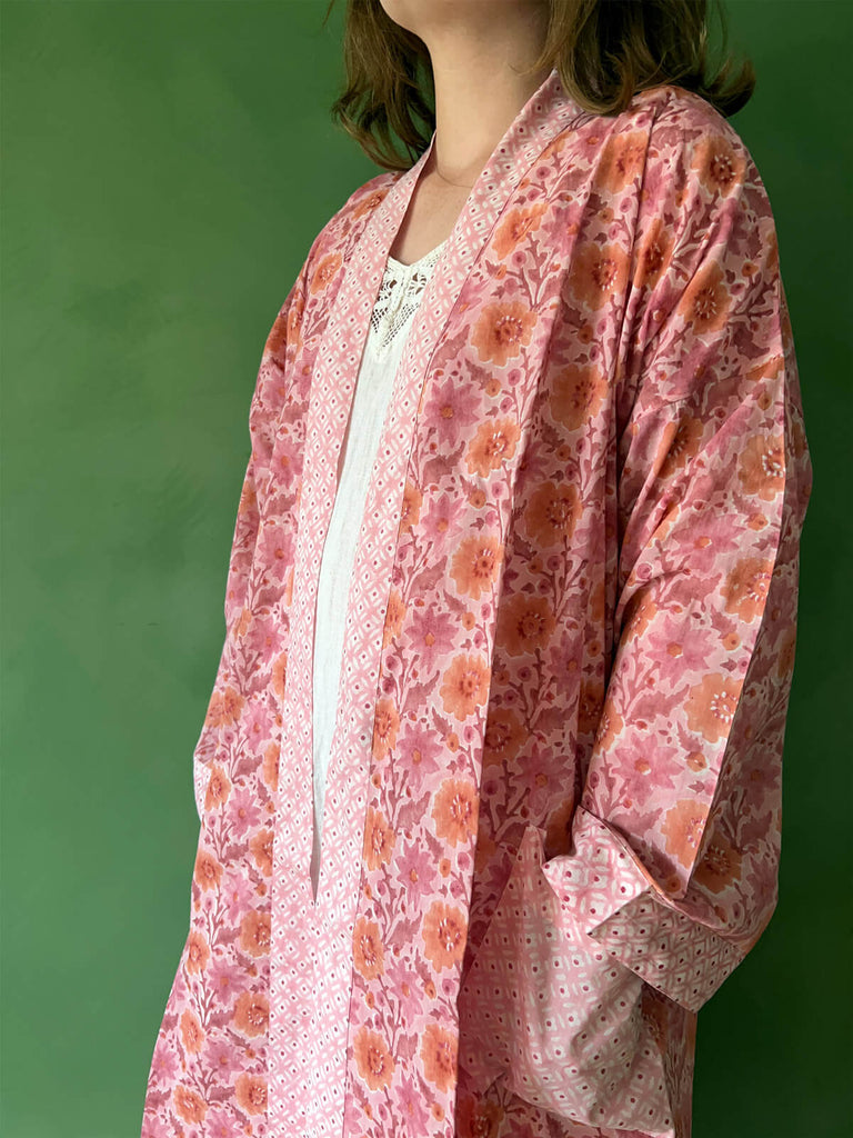 A close-up of a model wearing Bohemia floral block print cotton robe with contrasting pockets and trim in vintage pink.