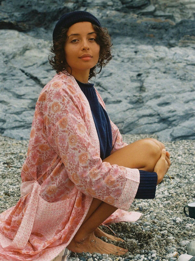 Model wearing a block print vintage pink floral robe on a pebble beach