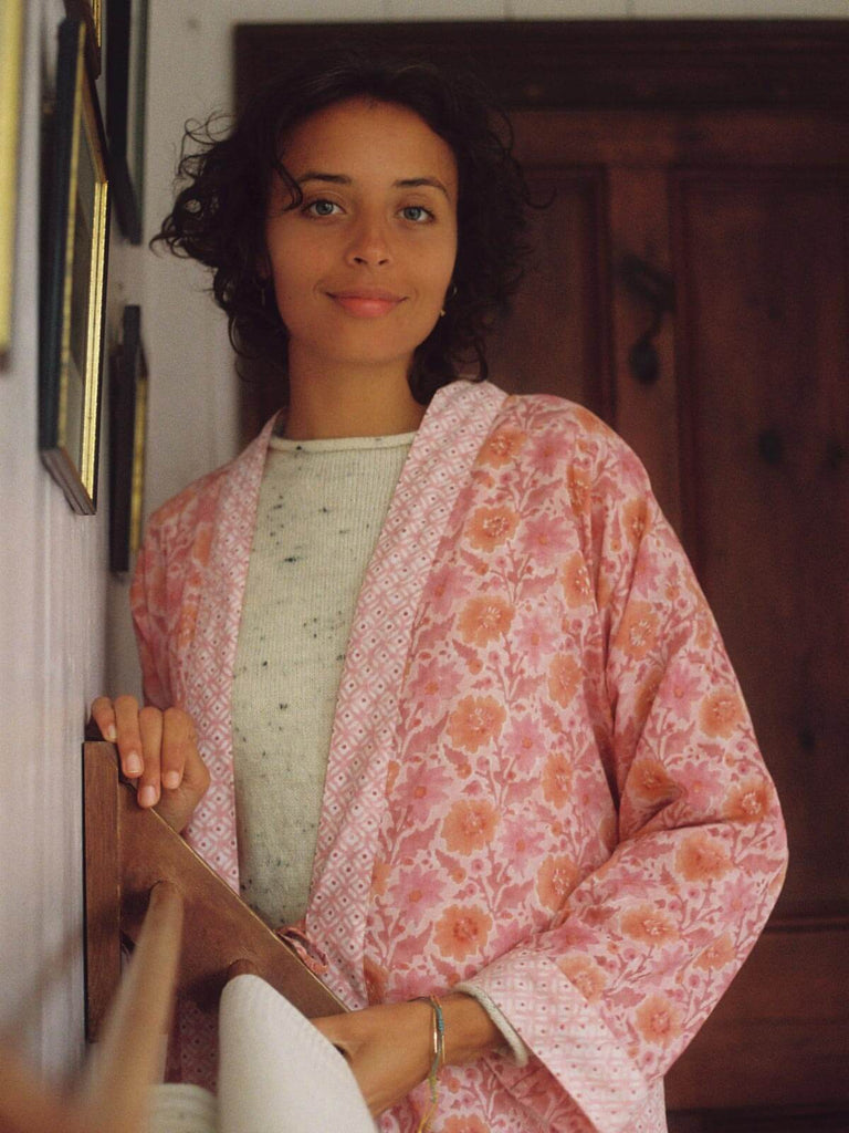 Model smiling wearing a vintage pink block print robe in a cottage bathroom