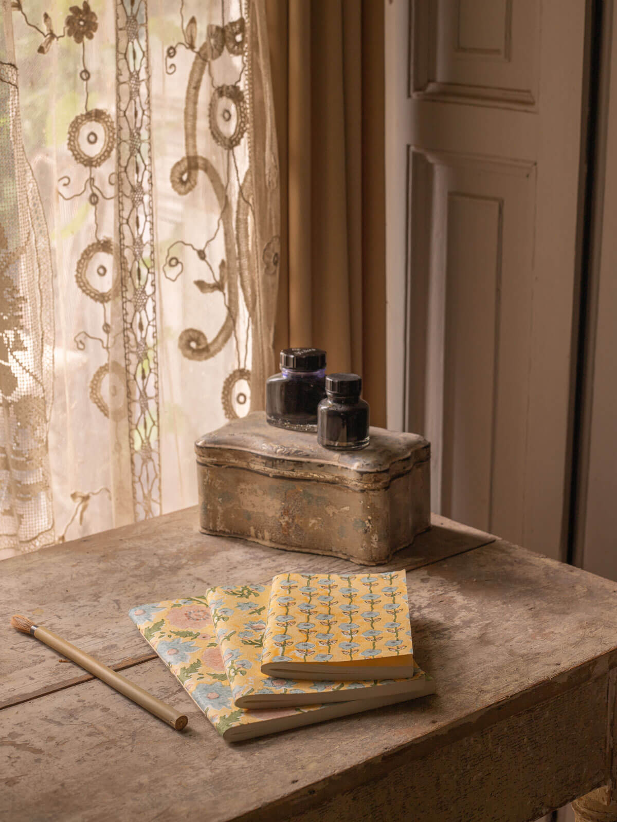 Set of 3 block printed buttermilk yellow floral notebooks on an antique desk