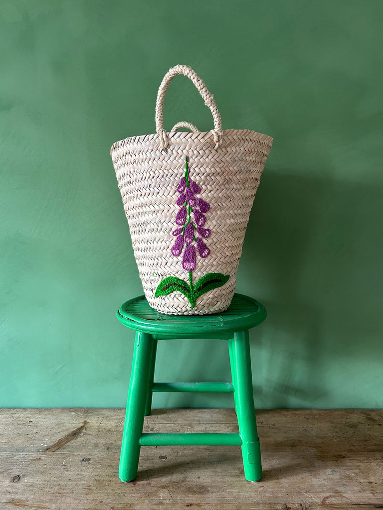 Hand-embroidered bucket basket bag with a Foxglove floral motif against a vibrant green backdrop by Bohemia Design