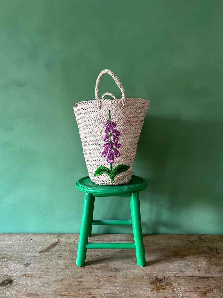 Hand embroidered basket bag on a green stool against a green wall | Bohemia Design