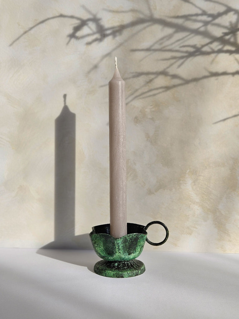 Iron candle holder in vintage moss finish with a candle against textured wall with natural light and subtle shadows | Bohemia