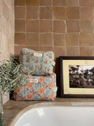 Floribunda and Posie cotton quilted washbags in soft duck egg with touches of terracotta and pale blue, displayed against natural stone tiles in a calm, neutral-toned bathroom | BohemiaDesign