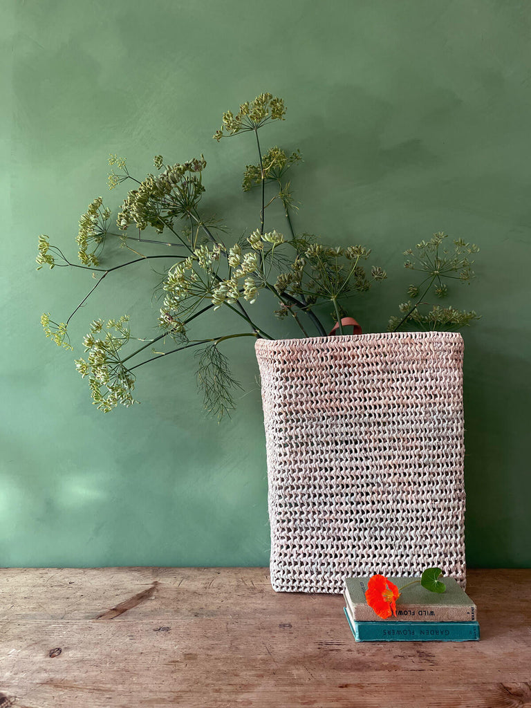 Osaka open weave hanging storage basket placed on a wooden table against a green wall | Bohemia Design