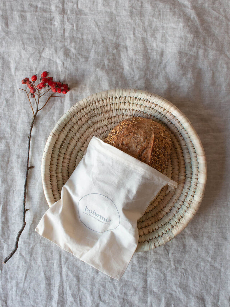 Large palm leaf woven plate with rustic bread and festive red berries