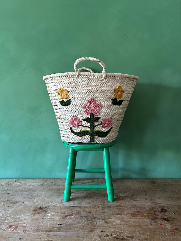 Hand embroidered market basket with two short handles, featuring our posy floral design, set against a vibrant green wall by Bohemia