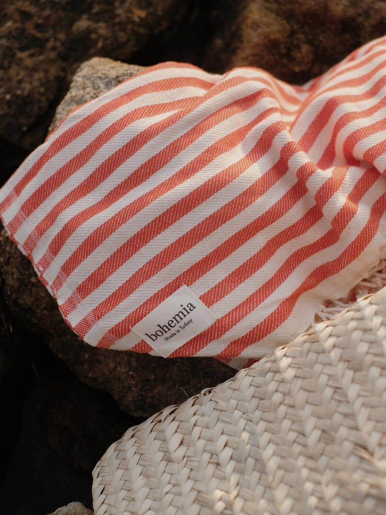 Close up of a Sorrento classic stripe hammam towel with Bohemia label on a rocky shore