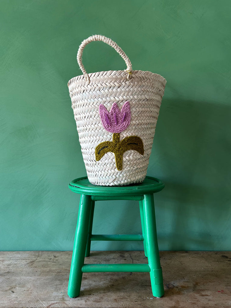 Hand embroidered bucket basket with a Tulip motif on a green stool against a green wall | Bohemia Design