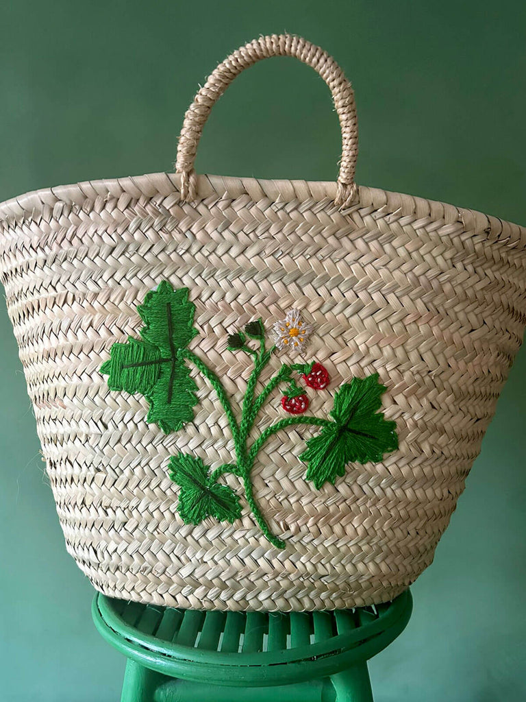 A close-up view of a wild strawberry motif intricately embroidered onto a natural hand-woven basket bag | Bohemia Design 